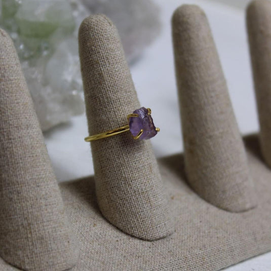 A a Raw Amethyst Ring with a gold vermeil prong setting on a ring stand