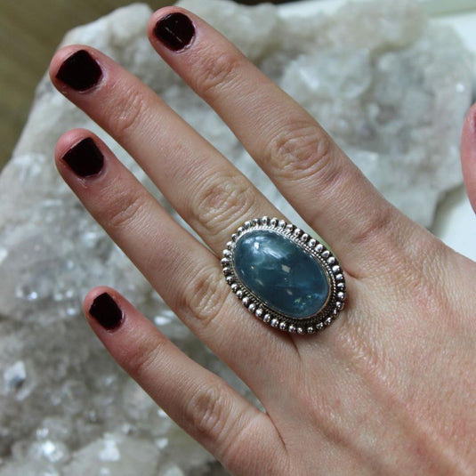 A stunning oval-cut Aquamarine stone set in a silver ring, showcasing its serene blue-green color.