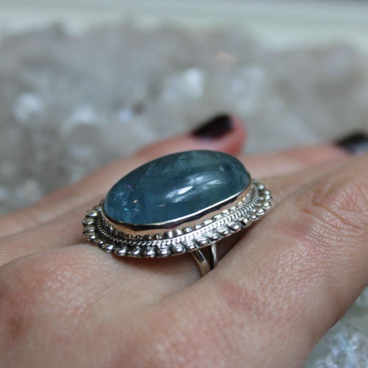 A stunning oval-cut Aquamarine gemstone set in a silver ring, showcased on a womans hand