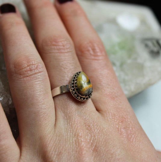 Bumblebee Jasper Sterling Silver Ring on a hand, resting on a crystal cluster.