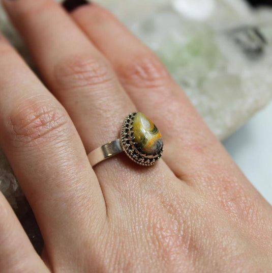 Bumblebee Jasper Sterling Silver Ring on a hand, resting on a crystal cluster.