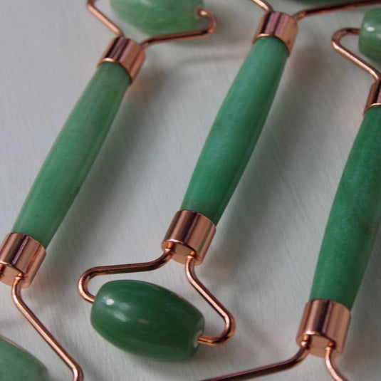 Three green aventurine massage rollers with rose gold handles