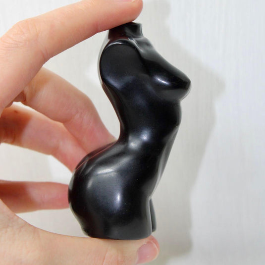 A sleek, black obsidian sculpture depicting a stylized female torso.