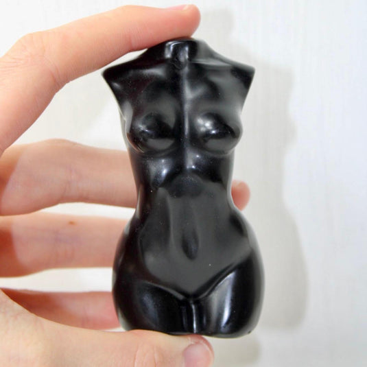 A sleek, black obsidian sculpture depicting a stylized female torso.