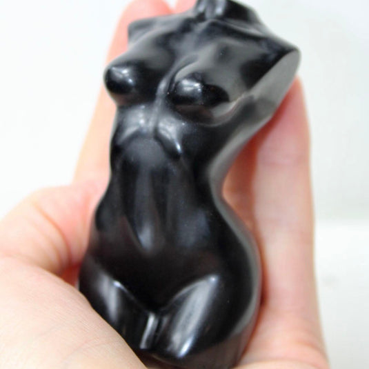 A sleek, black obsidian sculpture depicting a stylized female torso.