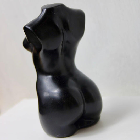 A sleek, black obsidian sculpture depicting a stylized female torso.