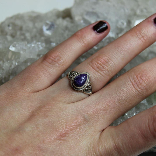 The intricate details of the silver band complement the beauty of the charoite.