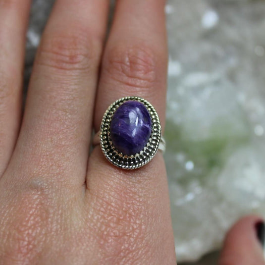 A stunning large oval Charoite gemstone set in a sterling silver ring with a beaded border.