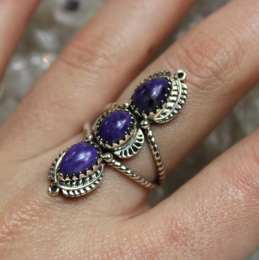 Charoite ring with three purple gemstones.