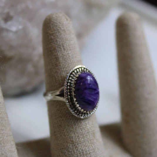 A close-up of a beautiful Charoite ring on a ring sizer, showcasing the vibrant purple and lavender hues of the gemstone.