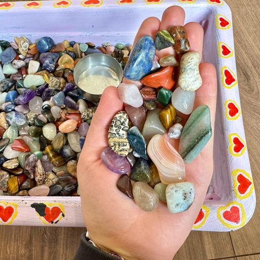 An example of a scoop of stones from the crystal confetti basket below, being displayed laid out on a hand.