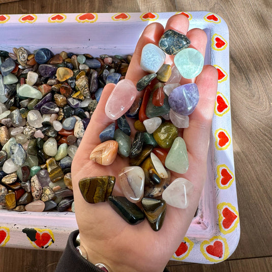 Another example of a scoop of stones from the crystal confetti basket below, being displayed laid out on a hand.