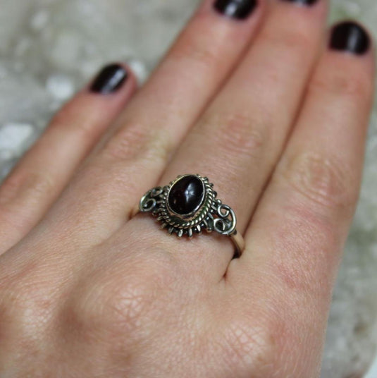 A person wearing a ring with a red oval stone.