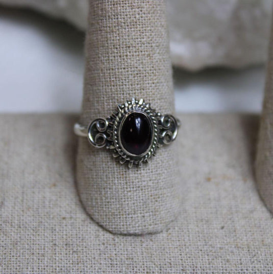 A deep red garnet stone set in a silver ring.