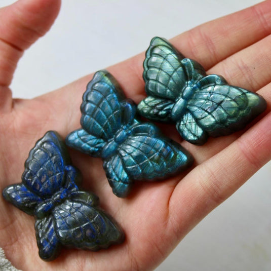 A collection of three labradorite butterfly carvings, showcasing the stone's iridescent blue and green hues.