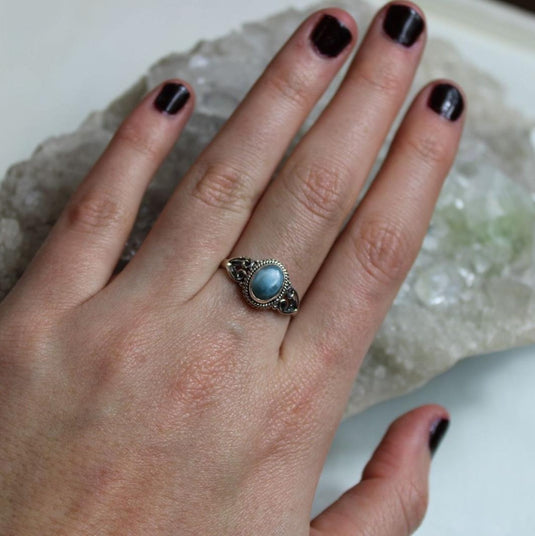 Hand wearing a Larimar ring on a crystals