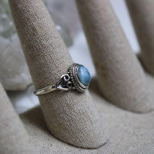 Side view of a Larimar ring on a ring stand, showcasing the silver band and intricate details.