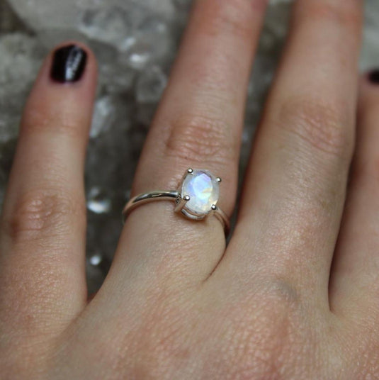 A captivating moonstone ring on a hand with dark nails