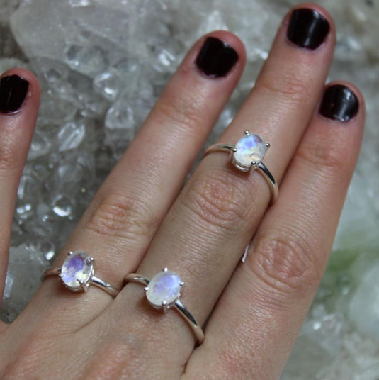 Three Moonstone rings on a hand with black nails