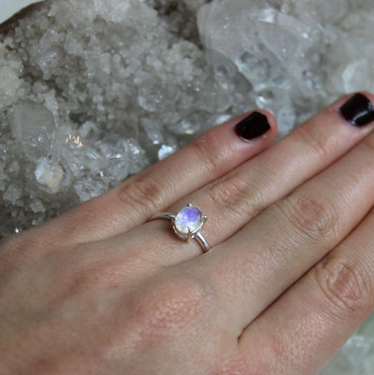 A captivating moonstone ring on a hand with dark nails