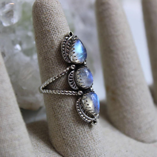 Bohemian tear drop-shaped moonstones with a beautiful blue flash in this silver ring on a ring stand