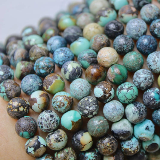 A group of round, earthy-toned Chinese Turquoise beads, showcasing the stone's unique colour variations.